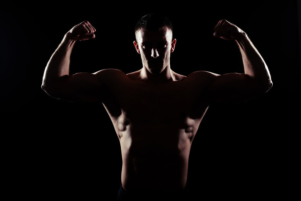 Silhouette of sexy athletic man on black background - Photo, Image