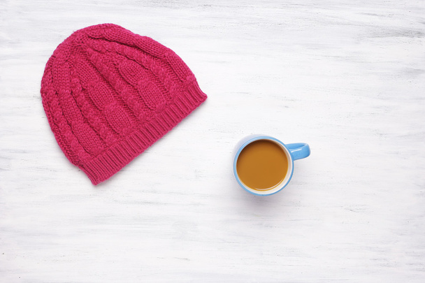 Top view of a cup of coffe and a knitted woman's hat - Foto, imagen