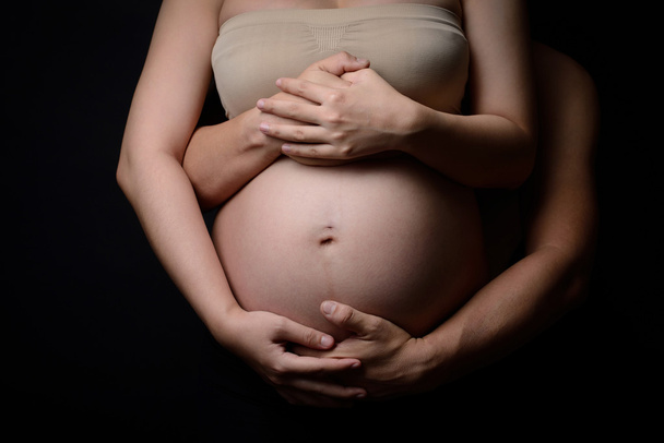 mani di donna incinta e suo marito sulla pancia
 - Foto, immagini