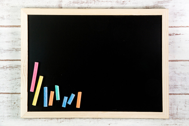 Lege Blackboard en kleur krijt op houten tafel. Sjabloon mock u - Foto, afbeelding