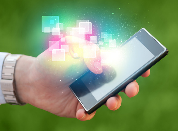 Hand holding smart phone with abstract glowing squares - Photo, Image