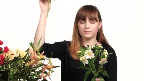 Florist assemble a bouquet of flowers. White. Close up - Materiał filmowy, wideo