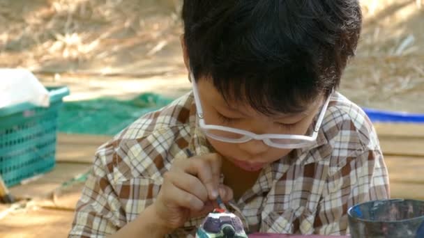 Ασιατικό παιδί ζωγραφίζει ένα αγαλματάκι .  - Πλάνα, βίντεο