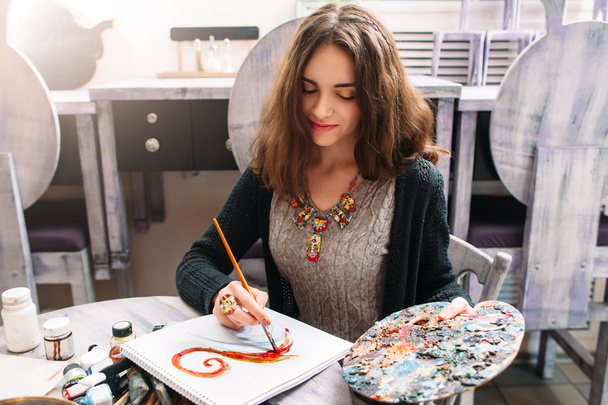 Pretty smiling woman drawing at studio - Foto, Imagem