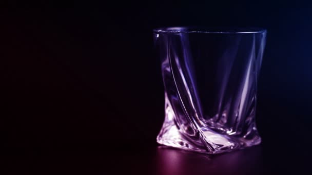 Whiskey wordt gegoten in een glas tegen zwarte achtergrond. - Video