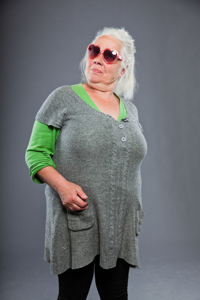 Senior woman wearing sunglasses with expressive face. Funny. Studio shot isolated on grey background. - Фото, зображення