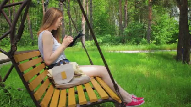 Chica joven en un columpio, lee la tableta de PC
 - Imágenes, Vídeo