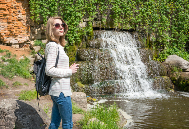 Mädchen steht in der Nähe eines Wasserfalls in einem Park - Foto, Bild