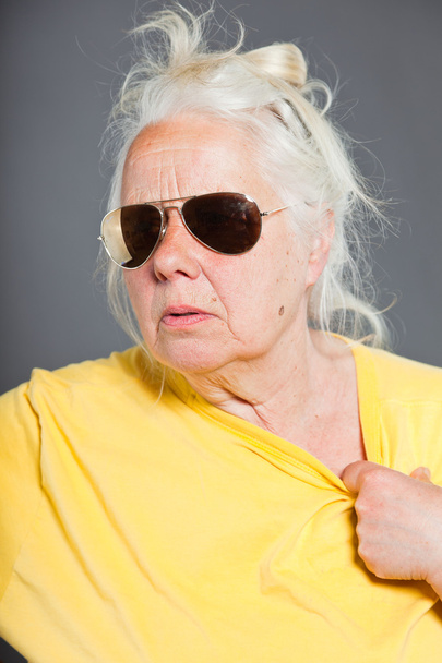 Cool hip senior woman with sunglasses and long grey hair. Expressive face. Studio shot isolated on grey. - Fotografie, Obrázek