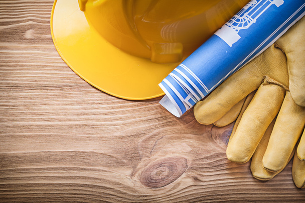 Blue rolled blueprint building helmet safety gloves on wooden bo - Foto, Imagen