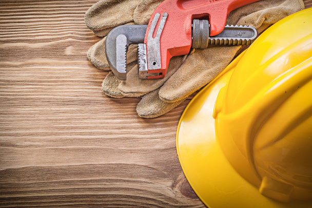 Hard hat safety gloves pipe wrench on wooden board construction  - 写真・画像