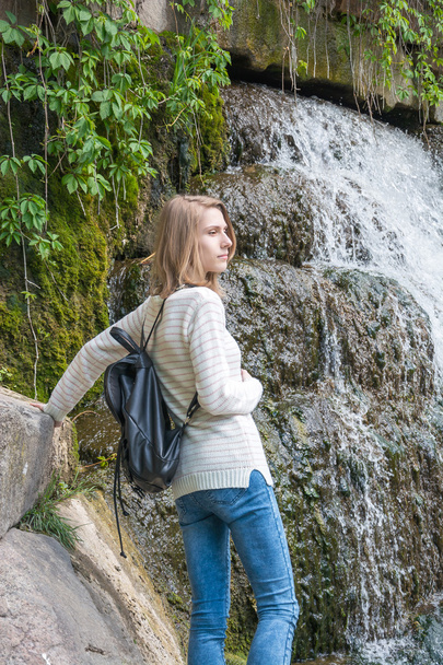 Girl standing near a waterfall in a park - Fotoğraf, Görsel