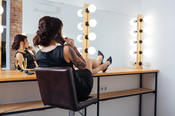 Woman sitting and talking on cell phone in dressing room - Foto, Imagen