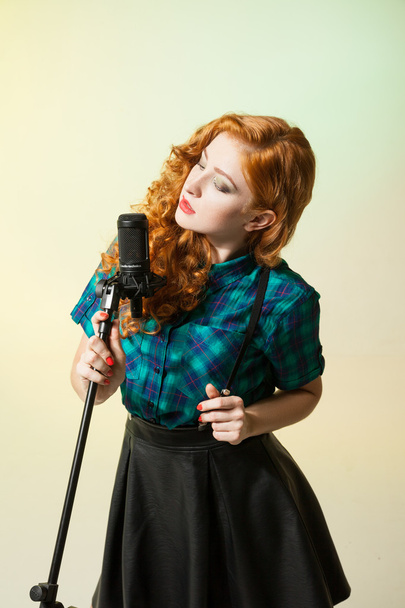 Portrait of beautiful red-haired woman singing in microphone - Fotoğraf, Görsel