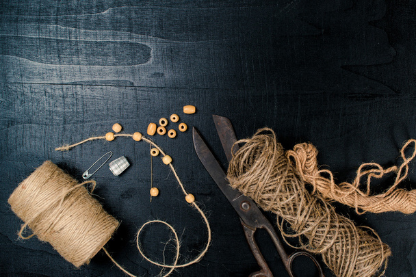 Set for needlework: scissors and skein jute twine on black background. Top view. - Fotografie, Obrázek