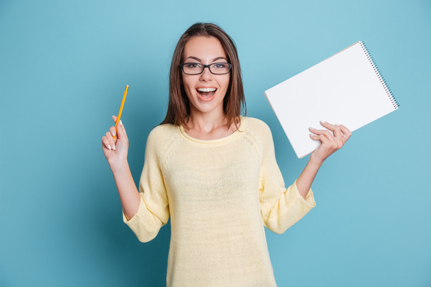 Laughing cheerful pretty girl holding notebook over blue background - Foto, Imagem