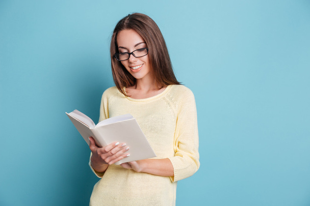 Young girl reading book over blue background - Φωτογραφία, εικόνα