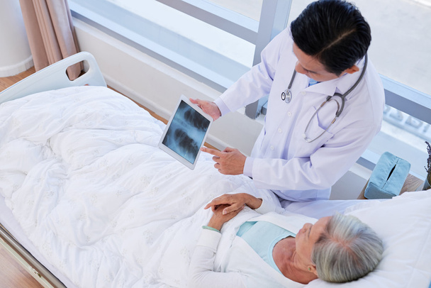 Médico mostrando radiografía pulmonar al paciente
 - Foto, imagen