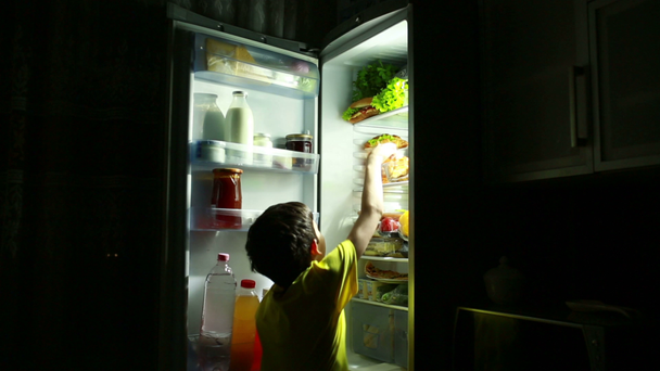 Gece yarısı buzdolabının önünde bir aperatif yemek çocuk. - Video, Çekim