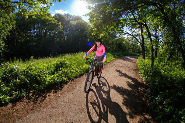 Fiatal nő birtoklás móka, lovaglás kerékpár a parkban. - Fotó, kép