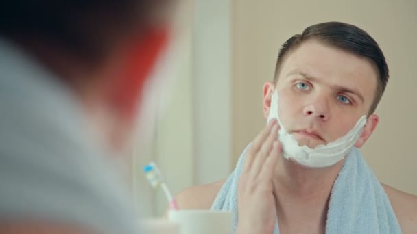 Nuori aikuinen mies peittää kasvot partavaahdolla ennen parranajoa
 - Materiaali, video