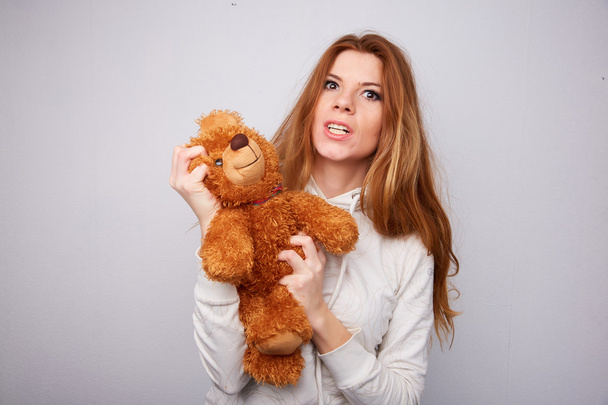 Beautiful girl breaks teddy bear - Foto, afbeelding
