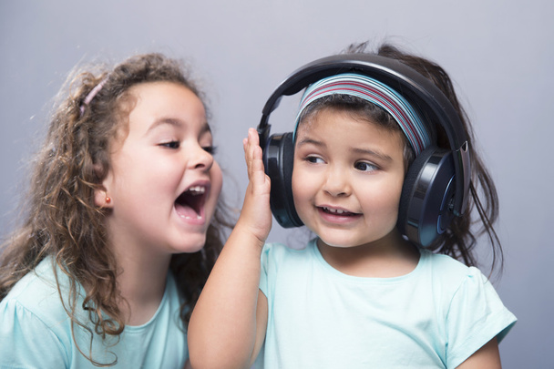 Older sister screaming at her younger sister in headphones - Foto, afbeelding