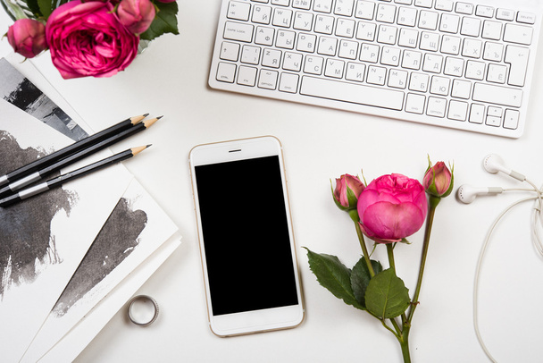 smartphone, tastiera del computer e fiori rosa su scheda bianca
 - Foto, immagini