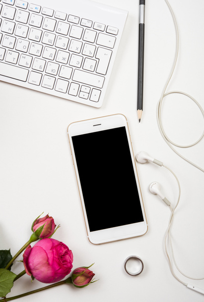 smartphone, számítógép-billentyűzet és fesh rózsaszín virágok fehér lap - Fotó, kép