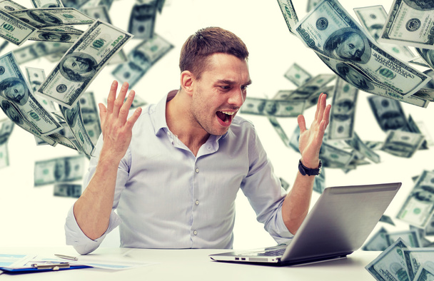 angry businessman with laptop and falling money - Zdjęcie, obraz