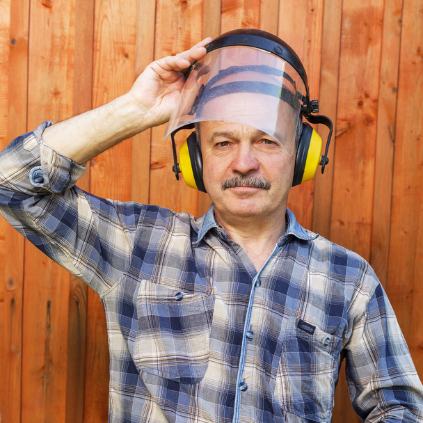 homem idoso em um edifício protetor fones de ouvido
 - Foto, Imagem