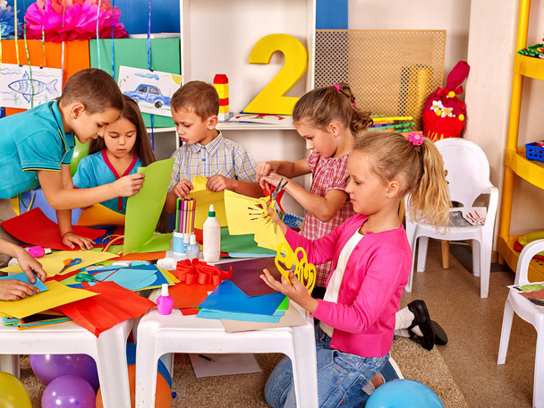 Lapset, joilla on värillinen paperi pöydällä päiväkodissa
 . - Valokuva, kuva