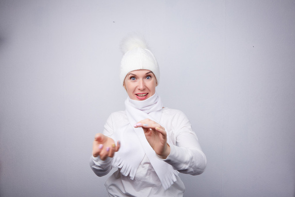 Blonde in white hat playing snowballs - Фото, изображение