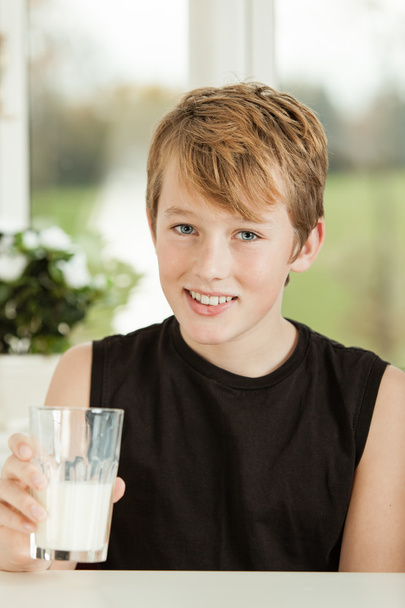 ミルクのガラスの 10 代の少年の笑顔 - 写真・画像
