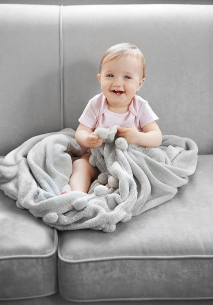 Baby girl on grey couch - Foto, afbeelding