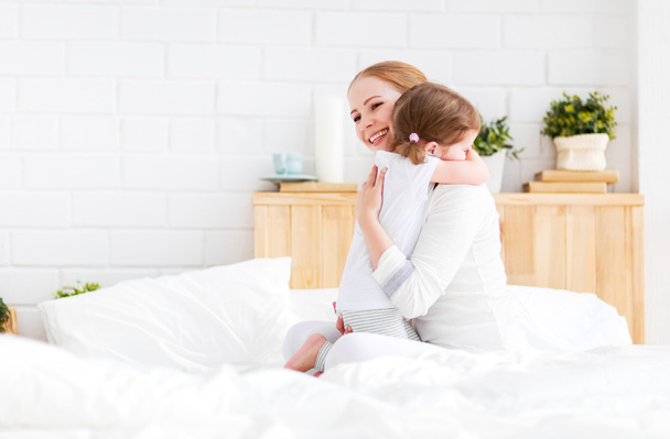 gelukkige familie moeder en kind omarmen van huging in bed  - Foto, afbeelding