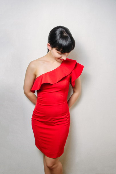 Krásná mladá model žena v červených šatech, které vystupují nad bílým pozadím - Fotografie, Obrázek