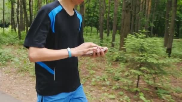 Νεαρός άνδρας, χρησιμοποιώντας το fitness βραχιόλι κατά τρέξιμο το πρωί - Πλάνα, βίντεο