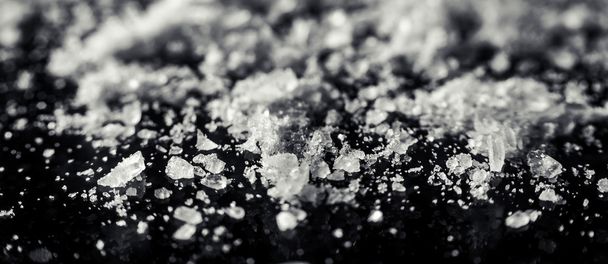 Κρύσταλλοι αλατιού, διάσπαρτα σε ένα μαύρο φόντο closeup - Φωτογραφία, εικόνα