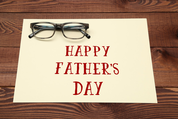 Happy Father's Day inscription with glasses on wooden background. - Фото, зображення