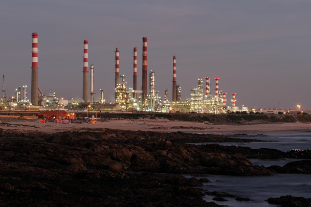 Olieraffinaderij in de buurt van de zee in de schemering - Foto, afbeelding