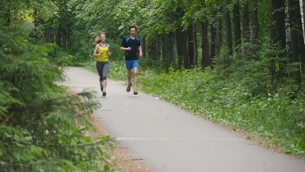 Szczęśliwa para joggingu w parku, w zwolnionym tempie - Materiał filmowy, wideo