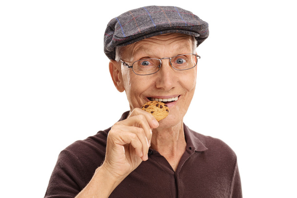Mature man eating a chocolate cookie  - Foto, afbeelding