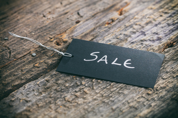 Closeup of pricing tag with twine and "Sale" text on wooden background - Foto, immagini