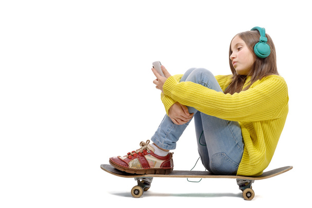 pretty young girl posing sitting on skate, listen  music - Foto, afbeelding