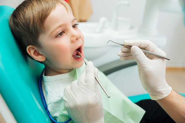 Boy sitting with mouth opened during oral checkup at dentist - Foto, Bild