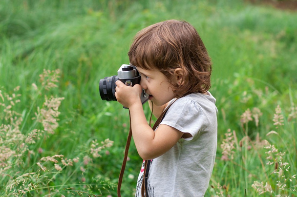 Kleines Mädchen fotografiert Blumen im grünen Gras - Foto, Bild
