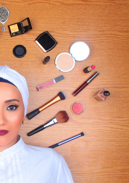 Woman in full makeup surrounded by makeup - Photo, Image