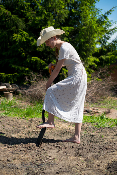 girl in a cowboy hat with a shovel digging a hole - Фото, изображение