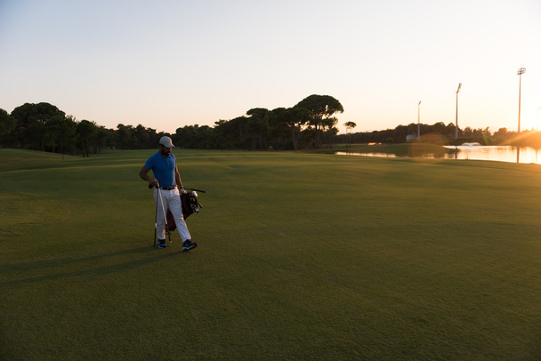 golfeur marchant et portant sac de golf au beau coucher de soleil
 - Photo, image